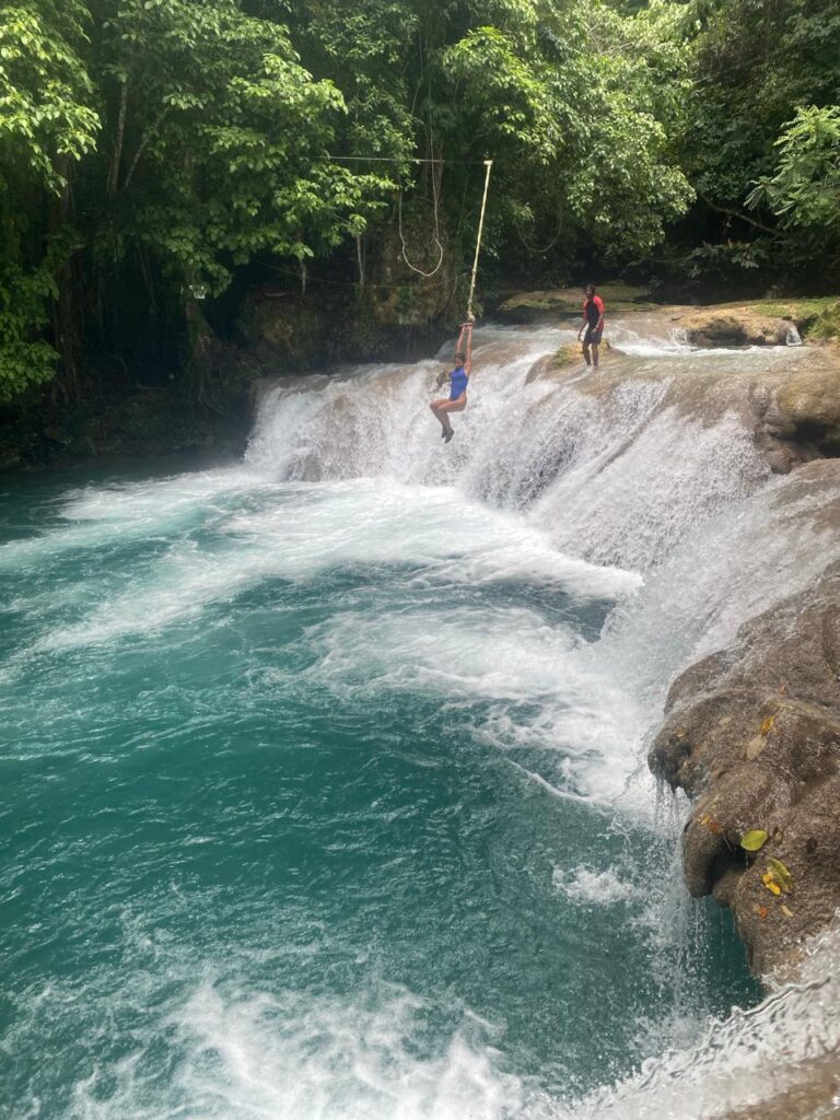 Visitors rope swing and exploring Blue Hole natural pools in Jamaica